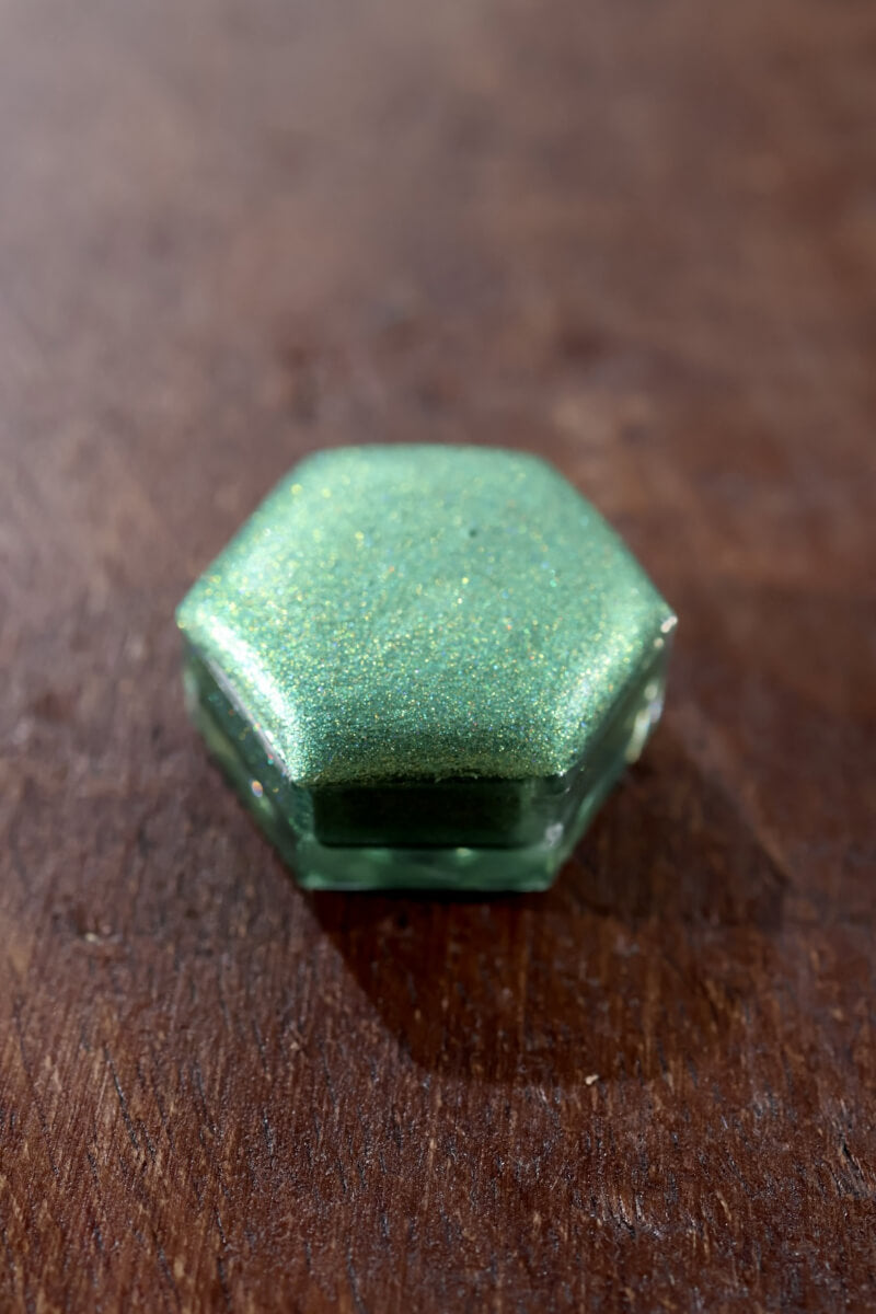 Holographic watercolor close-up showing prismatic light-reactive shimmer in a Lisilinka Opal pan