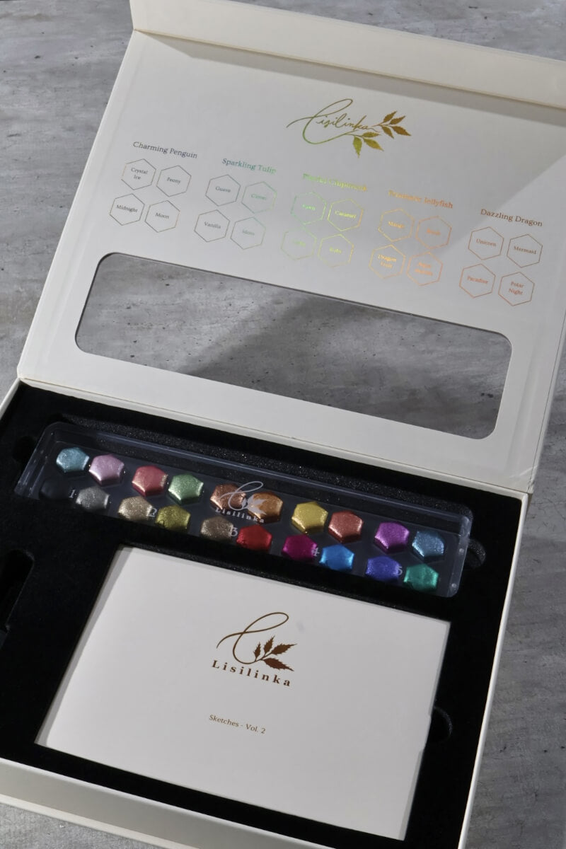 Full Tutorial Set Vol. 2 in hexagon size, open gift box with the twenty metallic watercolor pans in the acrylic box, swatch card with the five tutorial palettes printed inside the lid and the Sketches Vol. 2 folder