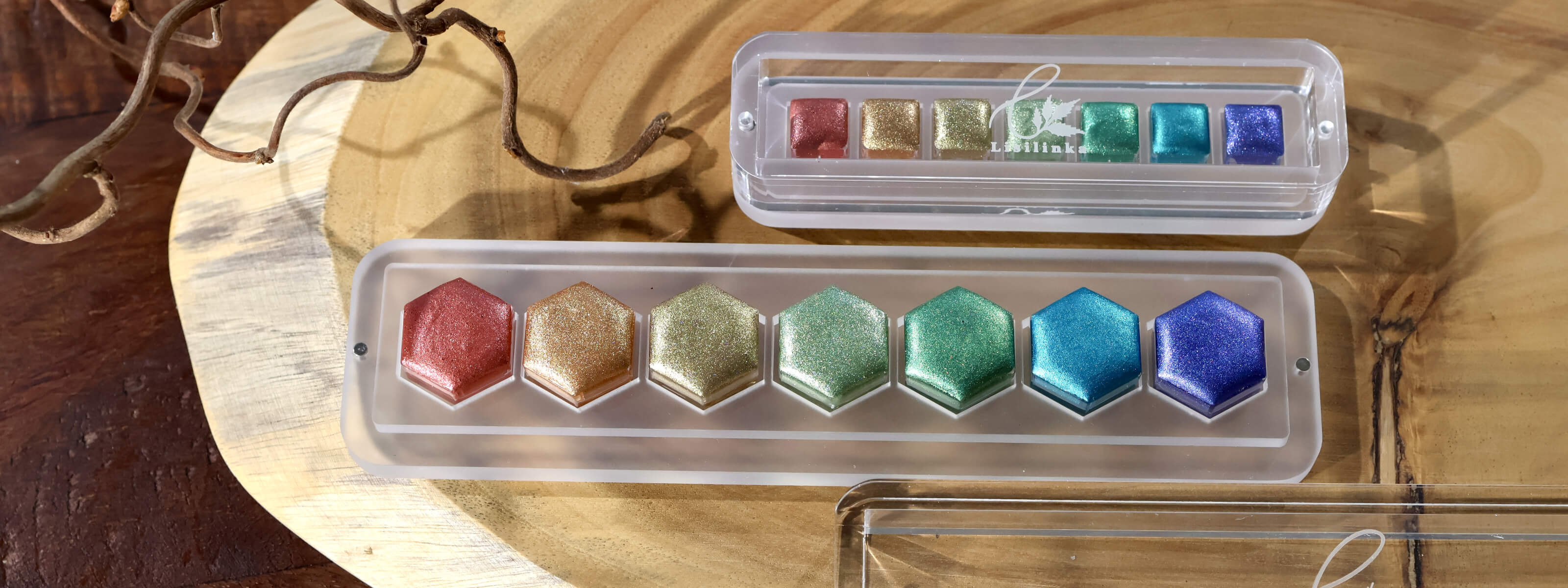 Lisilinka Opal set with six iridescent metallic watercolors in rainbow colors displayed in clear acrylic storage box on wooden surface