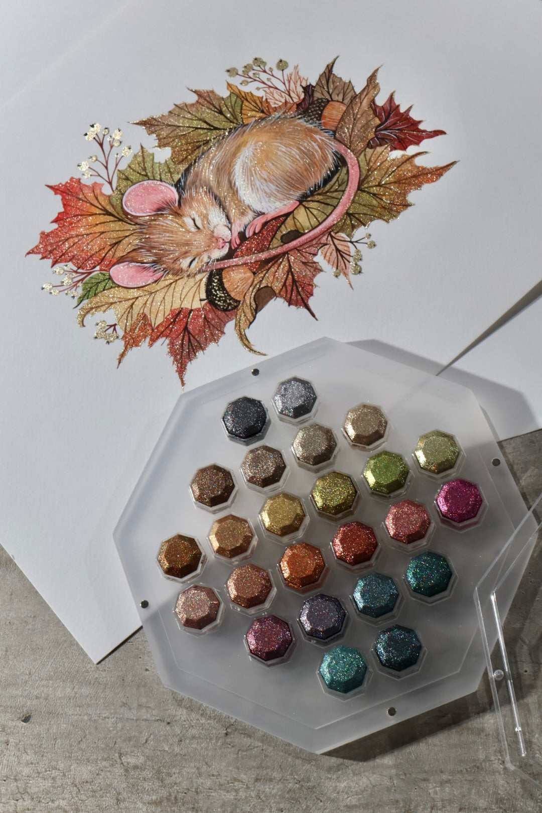 Mouse laying on leafes and the set of 24 colors in an acrylic tray