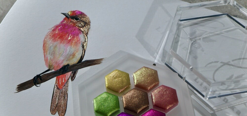 Pink bird on a branch painted with the Lisilinka Oasis set, hexagon pans beside it