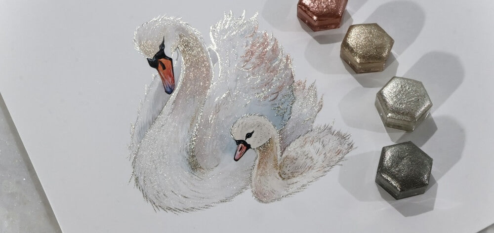 Sparkling swans painted with Lisilinka metallic watercolors next to hexagon pans